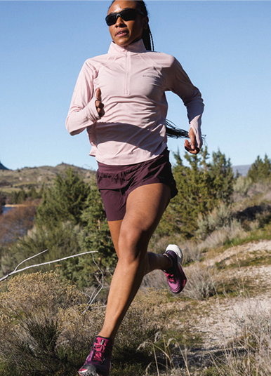 A woman trail running with clear skies. 