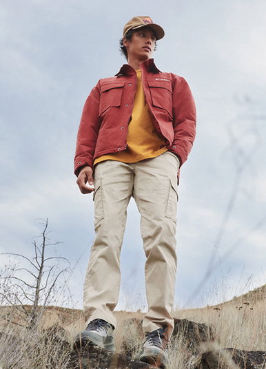 A model standing under partly cloudy skies and looking off to the side. 