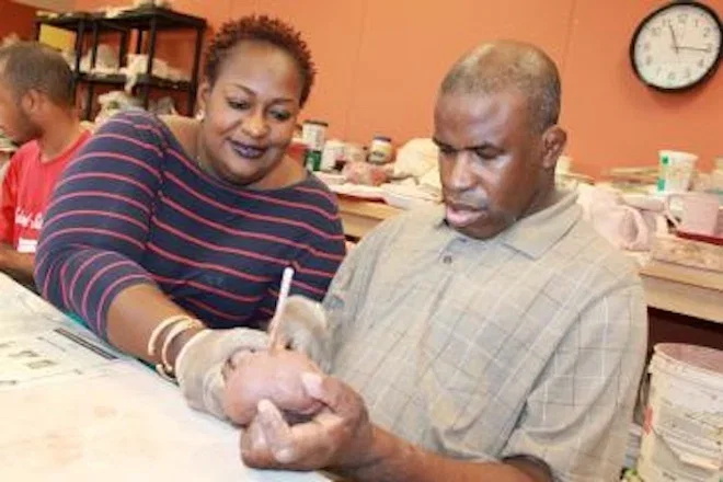 Instructor guides an adult through a hands-on activity in a classroom
