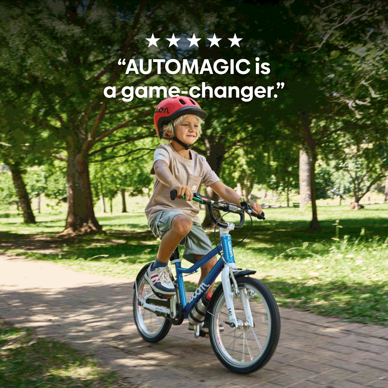A blond boy rides a woom GO 3 AUTOMAGIC through a park, with text above reading "AUTOMAGIC is a game changer." Five stars at the top of the image are animated to turn red one by one.