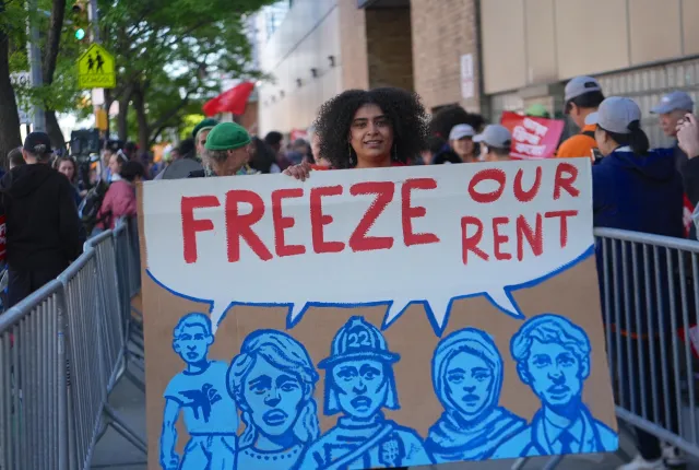 A woman holding a large cardboard sign saying 