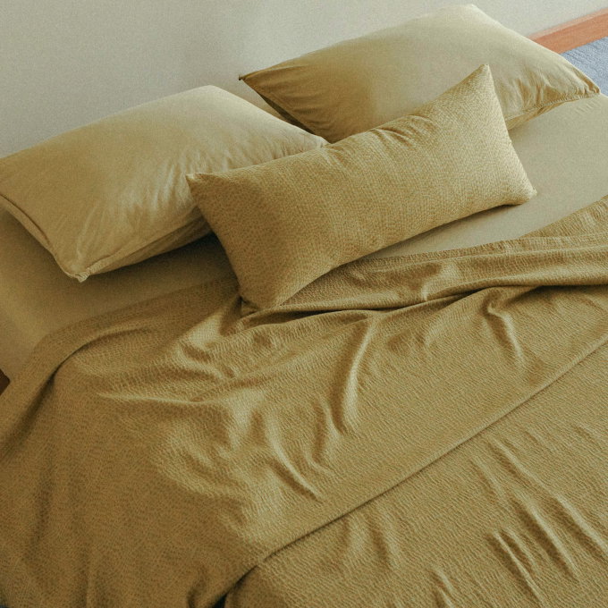 Green blanket and pillows on a bed