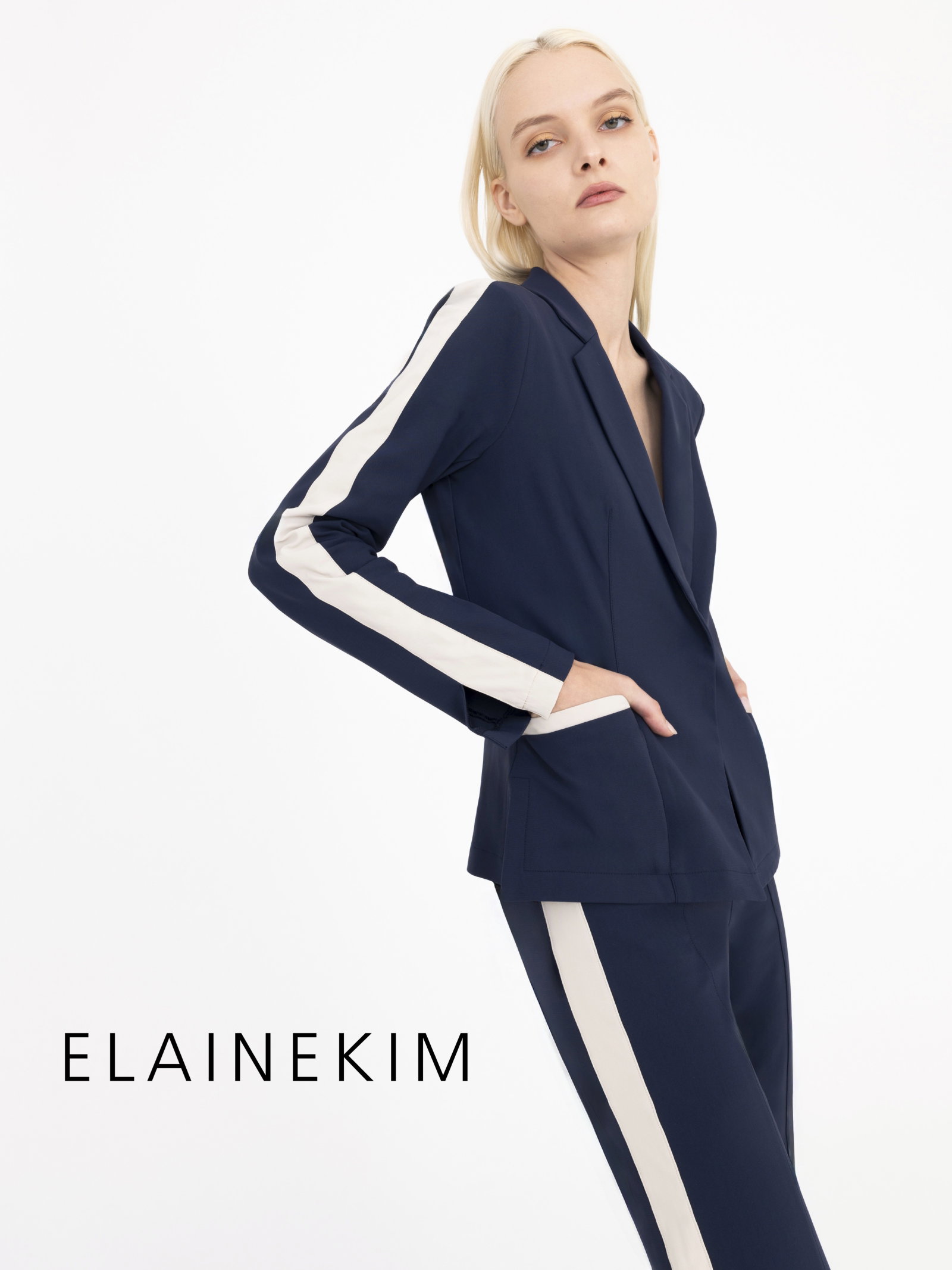 Woman wearing a navy blue suit with beige side stripe on a white background