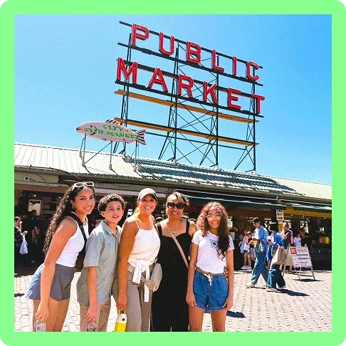 Image description: A family of five standing in front of the Pike Place Market sign in Seattle