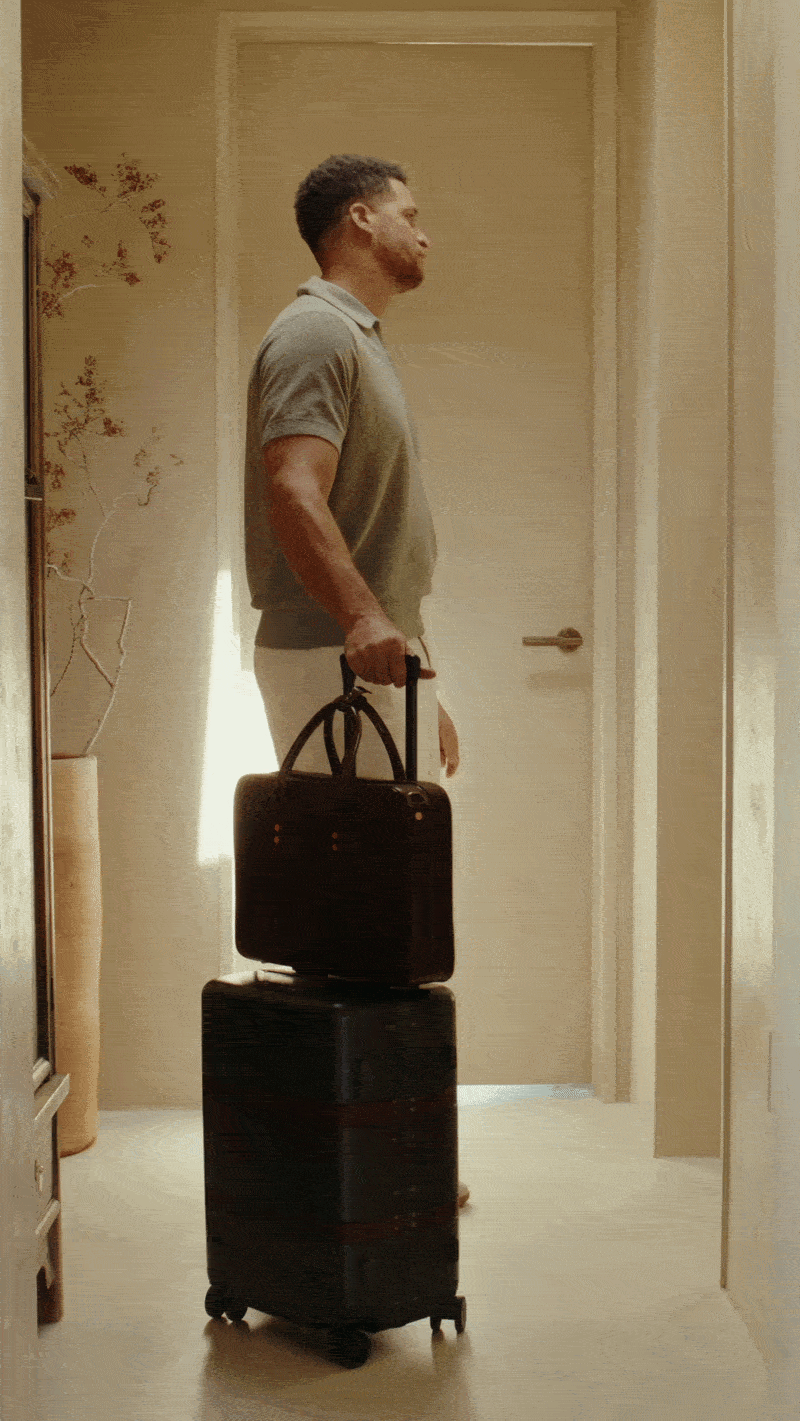 <GIF man spinning around his luggage waiting for an elevator>