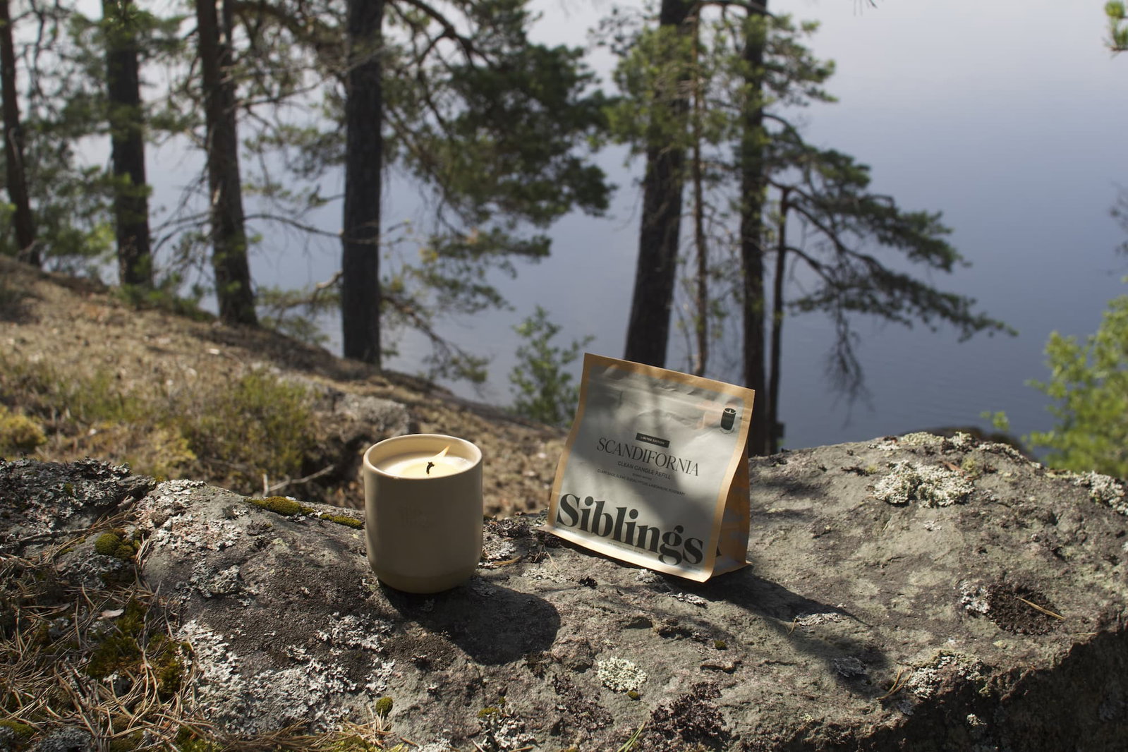 Scandifornia candle sitting in the forest near a Swedish lake