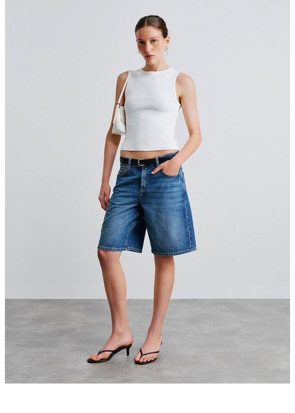 Woman wearing white tank top and blue denim shorts with sandals
