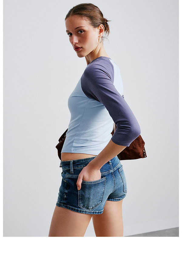 Woman wearing blue color-block long-sleeve top and denim shorts
