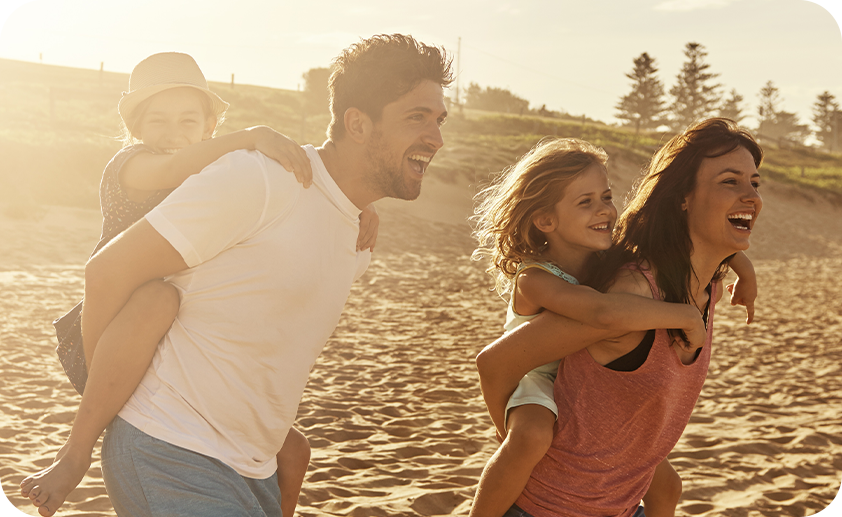 Fröhliche Familie mit zwei Kindern genießt gemeinsam einen sonnigen Tag am Strand.