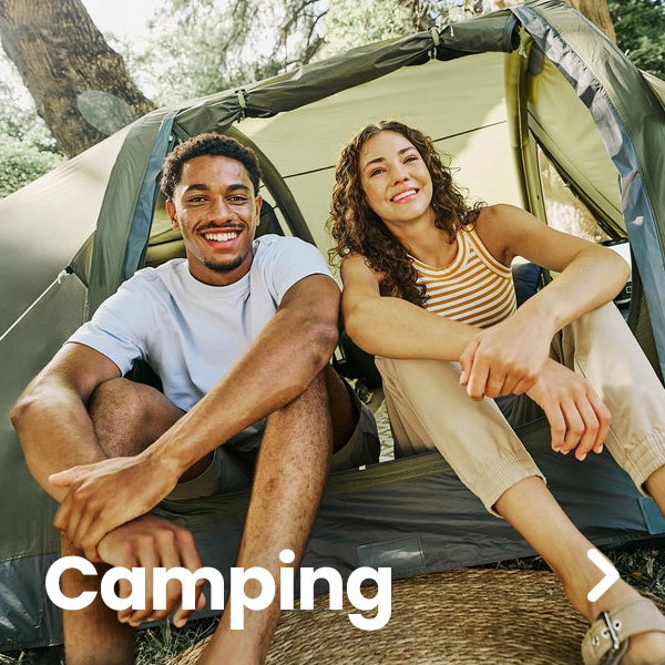 Two people sit at the entrance of a green camping tent in a wooded outdoor setting. One person wears a white T-shirt and shorts, while the other wears a striped sleeveless top and light-colored trousers. Large white text reading “Camping” appears in the lower-left corner, and a right-arrow navigation icon is displayed on the right side of the image. Sunlight filters through the trees in the background.