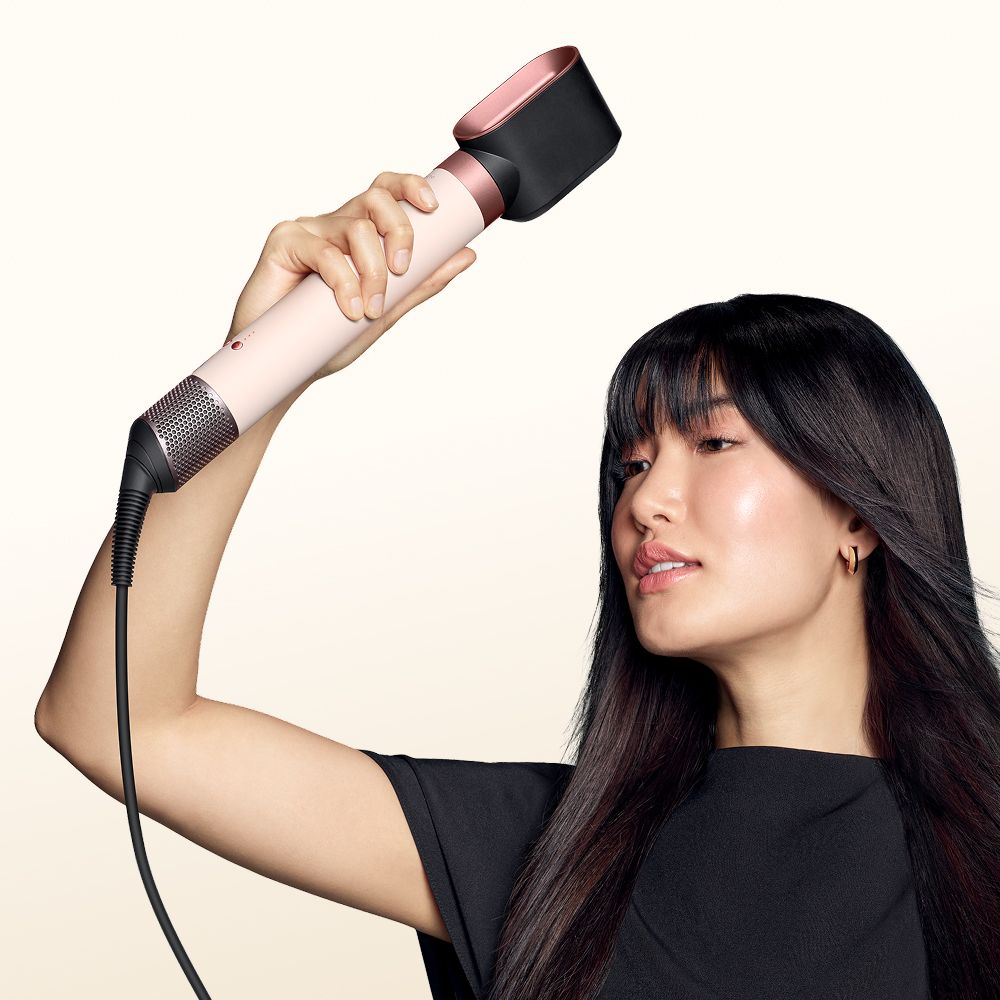 Model dries her hair with the Dyson Airwrap Co-anda2x multi-styler and dryer