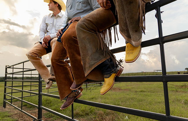 Three men wearing Boston 13" Whitetail Deer estern boots while sitting on a fence.