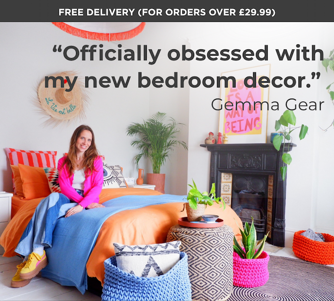 Gemma Gear says, “Officially obsessed with my new bedroom decor.” Shown sitting on a brightly styled orange and pink bed.