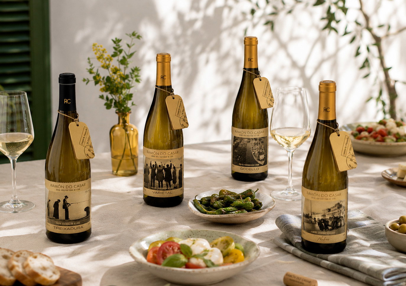 Four Ramón do Casar white wine bottles with glasses and tapas on a sunlit outdoor dining table, Mediterranean-style summer spread