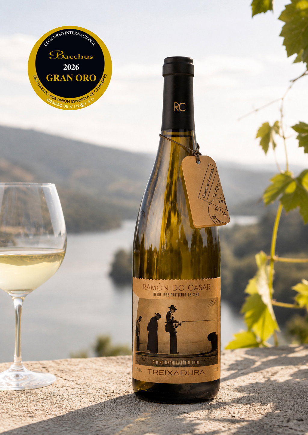 Bottle of Ramón do Casar Treixadura white wine and a glass on a stone ledge with a river valley backdrop and 2026 Gran Oro Bacchus award sticker