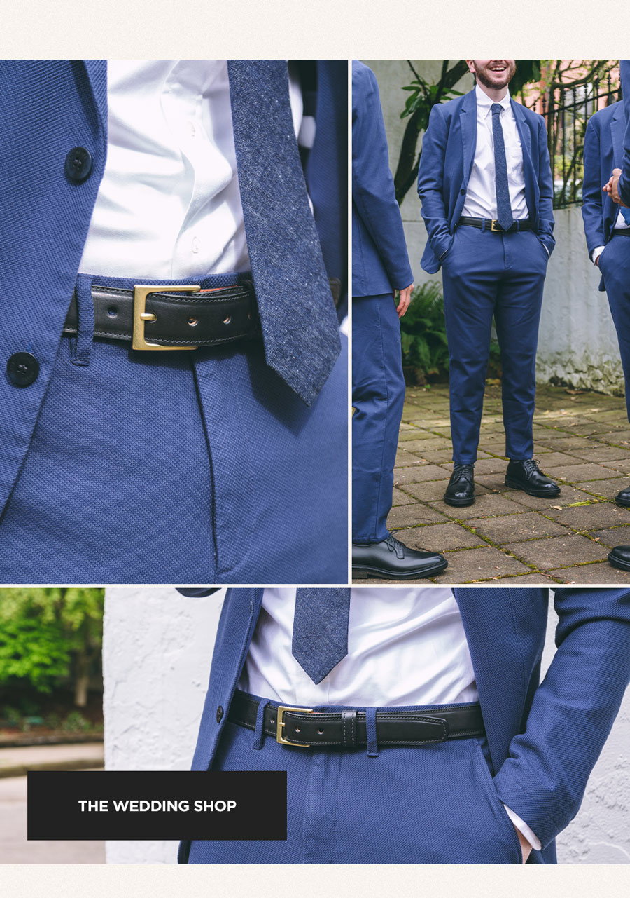 Three groomsmen standing around laughing wearing navy blue suits.