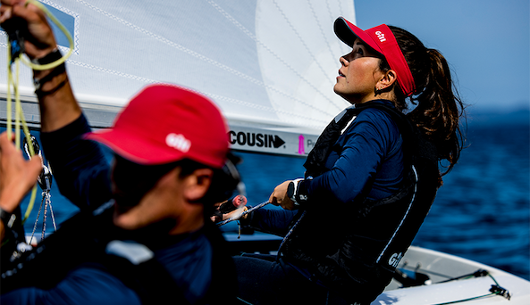 A woman on a boat holding a pursuit cap on her head