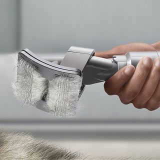 The Pet groom tool with of pet hair in the bristles being lifted off a pet.