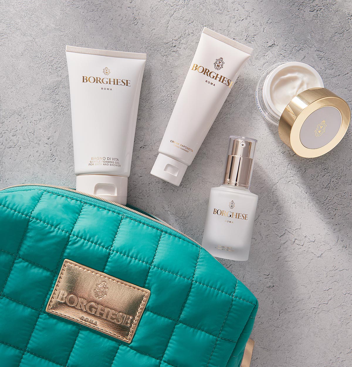 Product shot of Bagno di Vita travel size, Crema Saponetta travel size, Crema Ristorativo-24 travel size, and Curaforte travel size with the Borghese puffy bag.