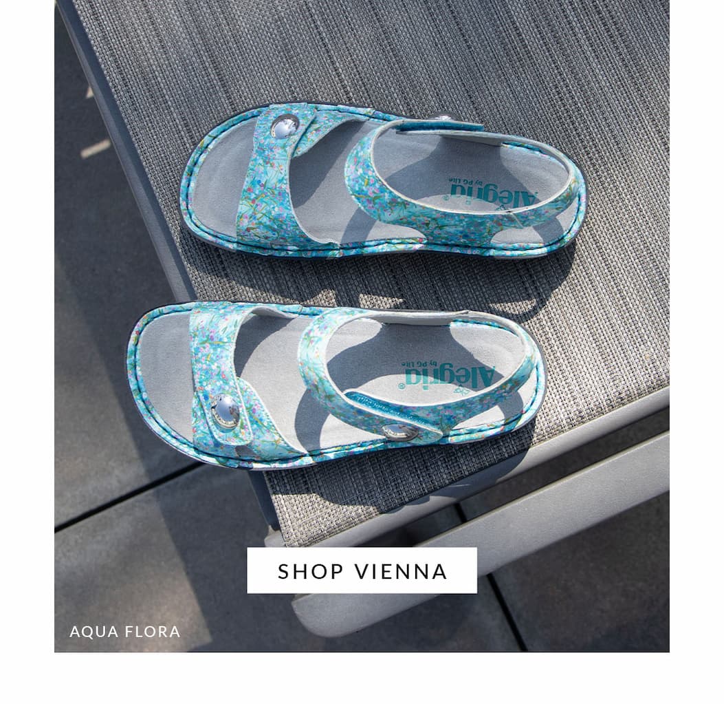 Top-down view of Alegria Vienna sandals in Aqua Flora print featuring adjustable hook-and-loop straps, a cushioned footbed, and lightweight comfort, displayed on an outdoor lounge chair.