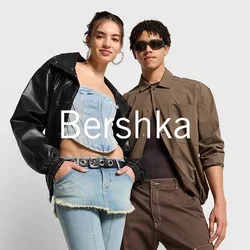 Twee individuen staan naast elkaar. De ene draagt een zwarte leren jas en een denim cropped top met hoge taille jeans. De ander draagt een bruin shirt en een broek.