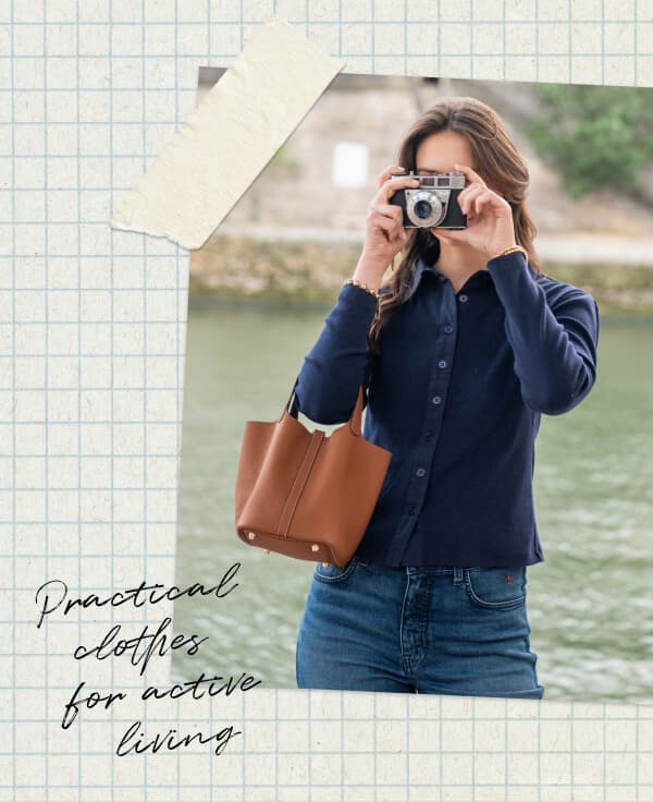 Practical clothes for active living - Image of a woman wearing a long sleeve navy collared knit top holding up a camera