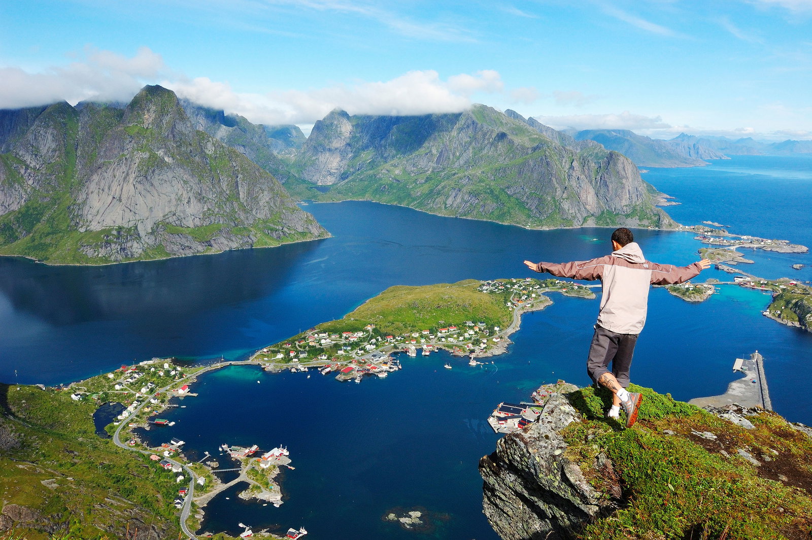 La aldea pesquera de Reine en Lofoten con sus rorbuer rojas reflejadas en el fiordo bajo cumbres rocosas