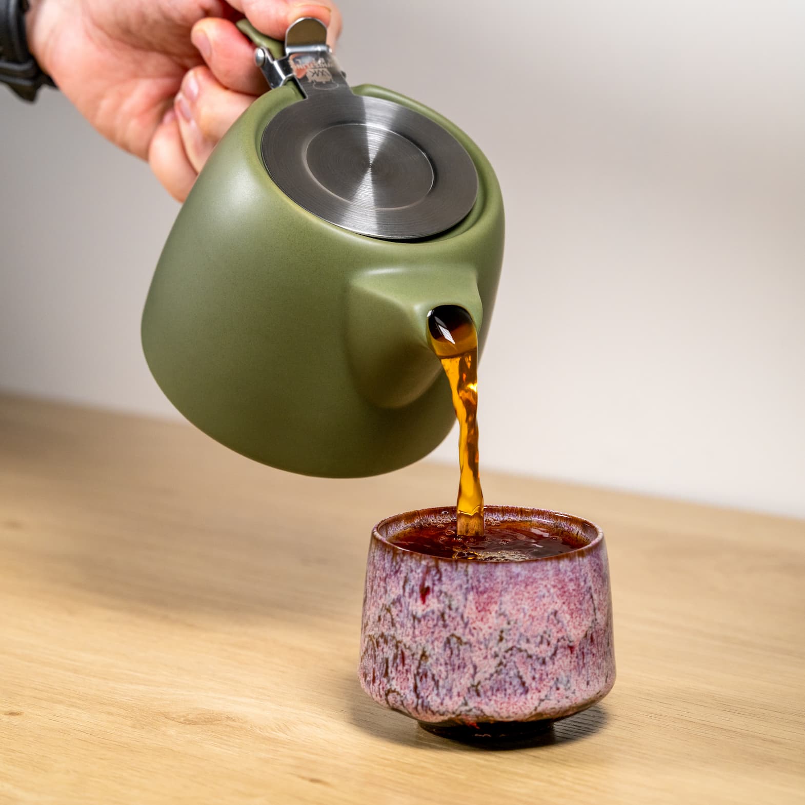 pouring tea from olive green nordic teapot