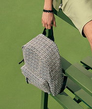 A closeup of a man holding a patterned backpack.