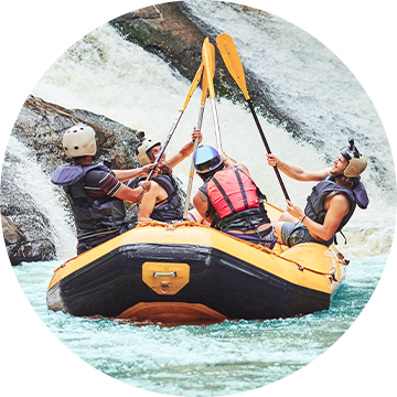 Personen sitzen in einem Rafting Boot.