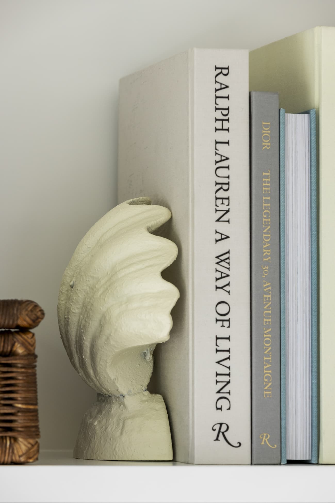 Ivory shell bookend holding up some books. 