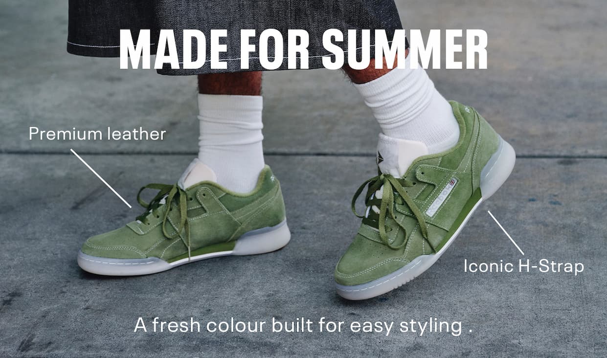 Close-up of olive green Reebok Workout Plus sneakers worn outdoors. Callouts highlight premium leather and the iconic H-Strap. Text reads: “MADE FOR SUMMER. A fresh colour built for easy styling.”