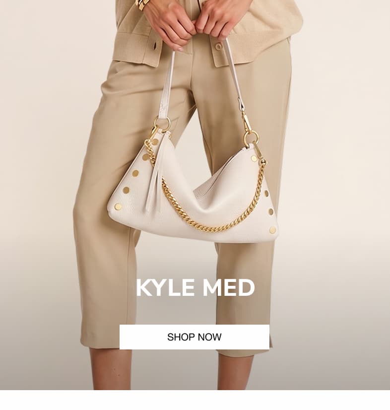 Model carrying the Hammitt Kyle Med in Calla Lily White pebbled leather with a gold chain strap.