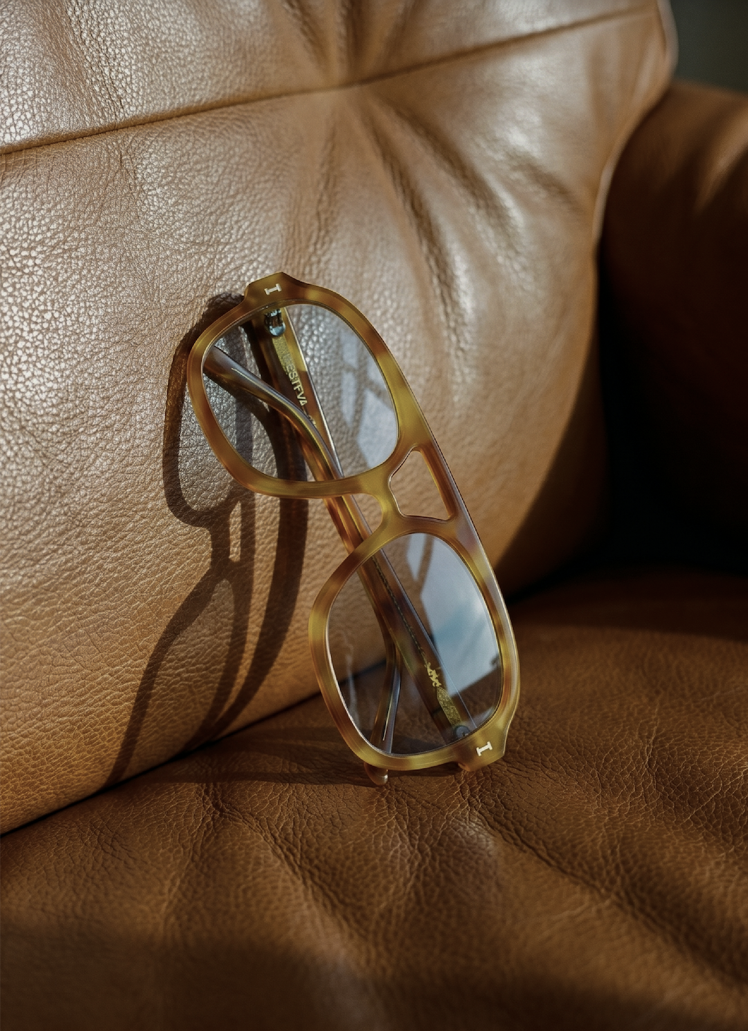 The Memphis Sunglasses in Amber against brown leather furniture