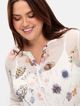 Model in weißer Chiffonbluse mit Blütendruck.