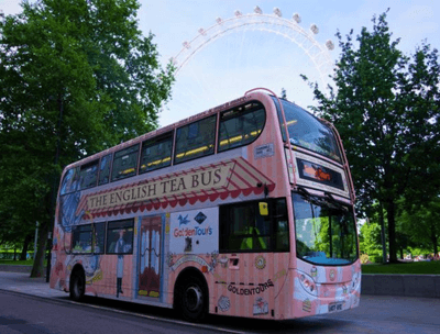 A pink double-decker bus promoting English tea, parked with the London Eye in the background.