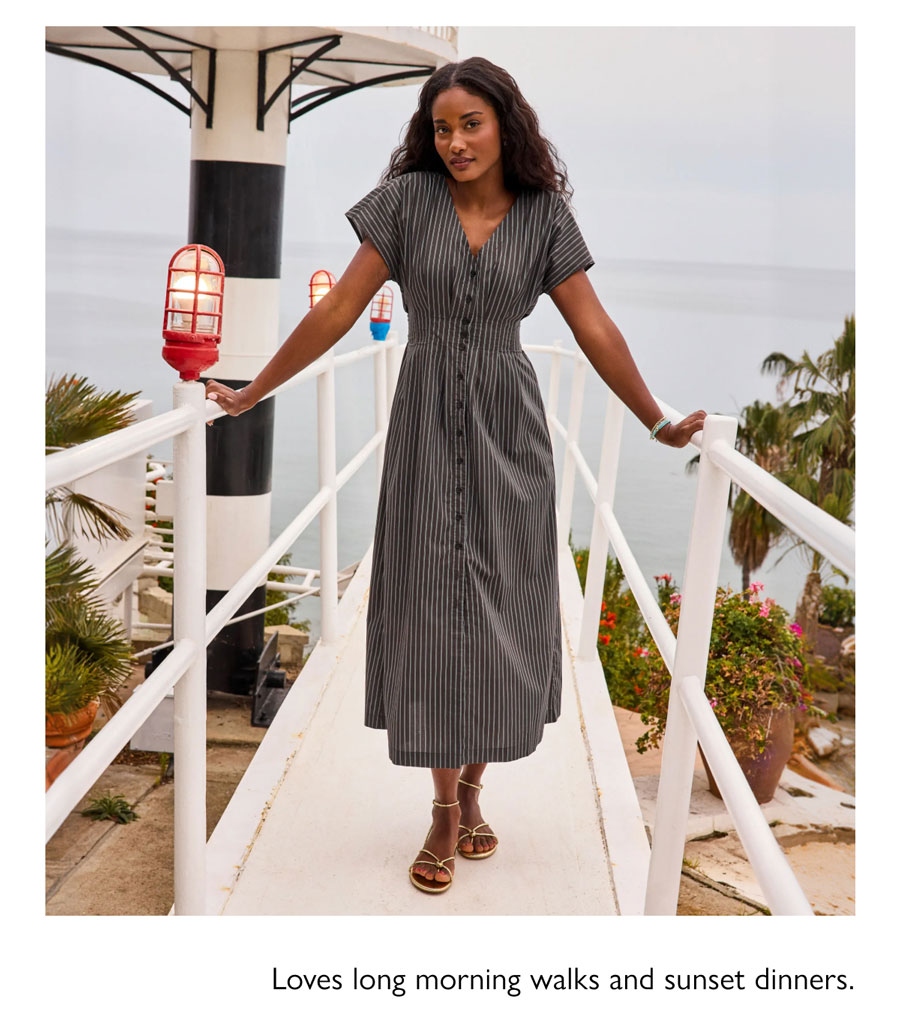 Loves long morning walks and sunset dinners. Model crossing bridge near beach in flowly striped dress from EVEREVE.
