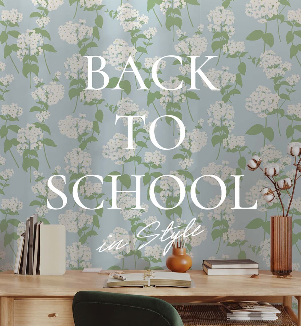 Image of Tempaper's Pop Hydrandgeas wallpaper in blue behind a desk with books and a vase with cotton blooms.