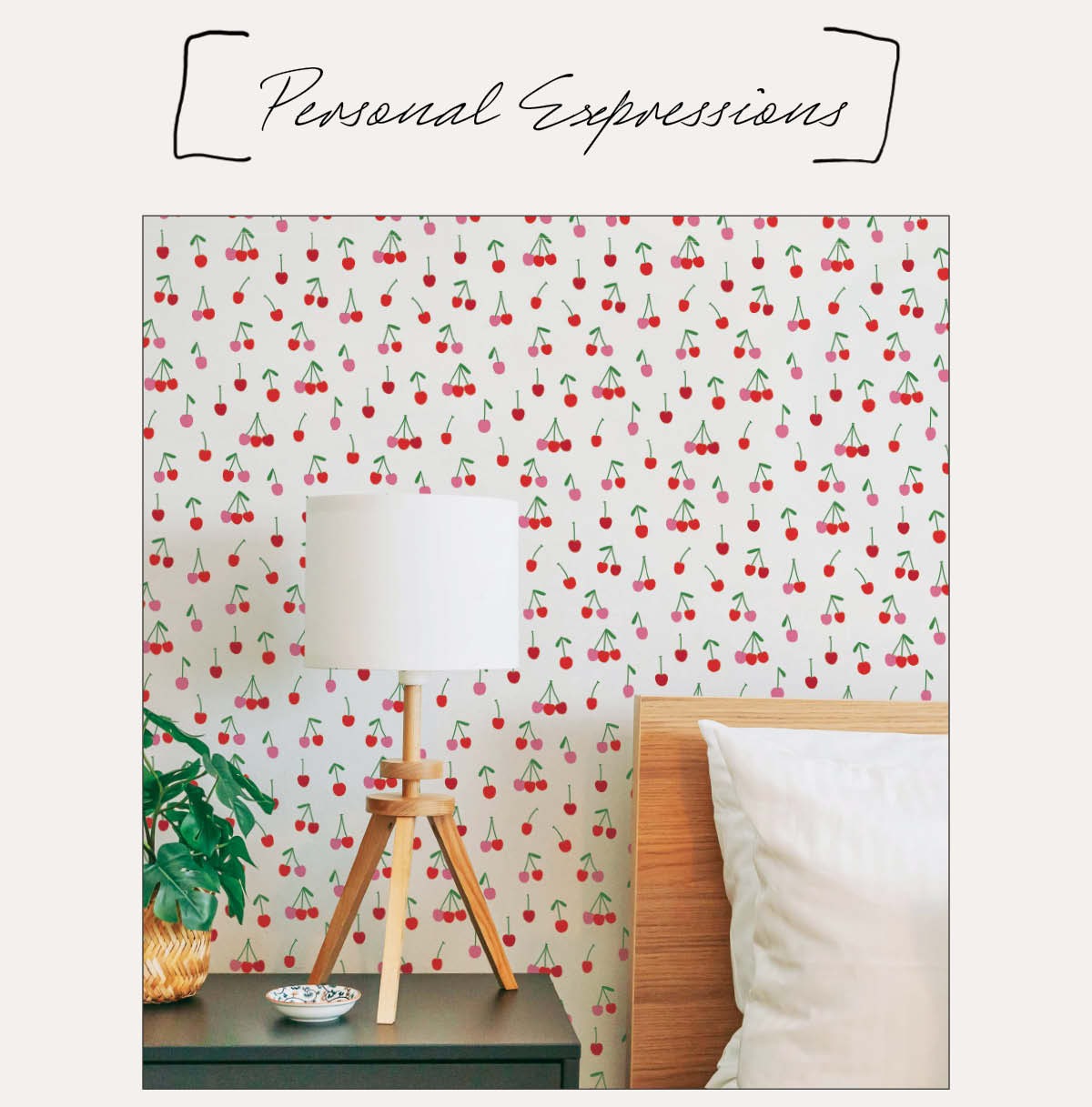 Image of Tempaper's Cherry Bomb wallpaper behind a bed with a wooden headboard next to a nightstand with a lamp with a wood tripod base. Text above "Personal Expressions"