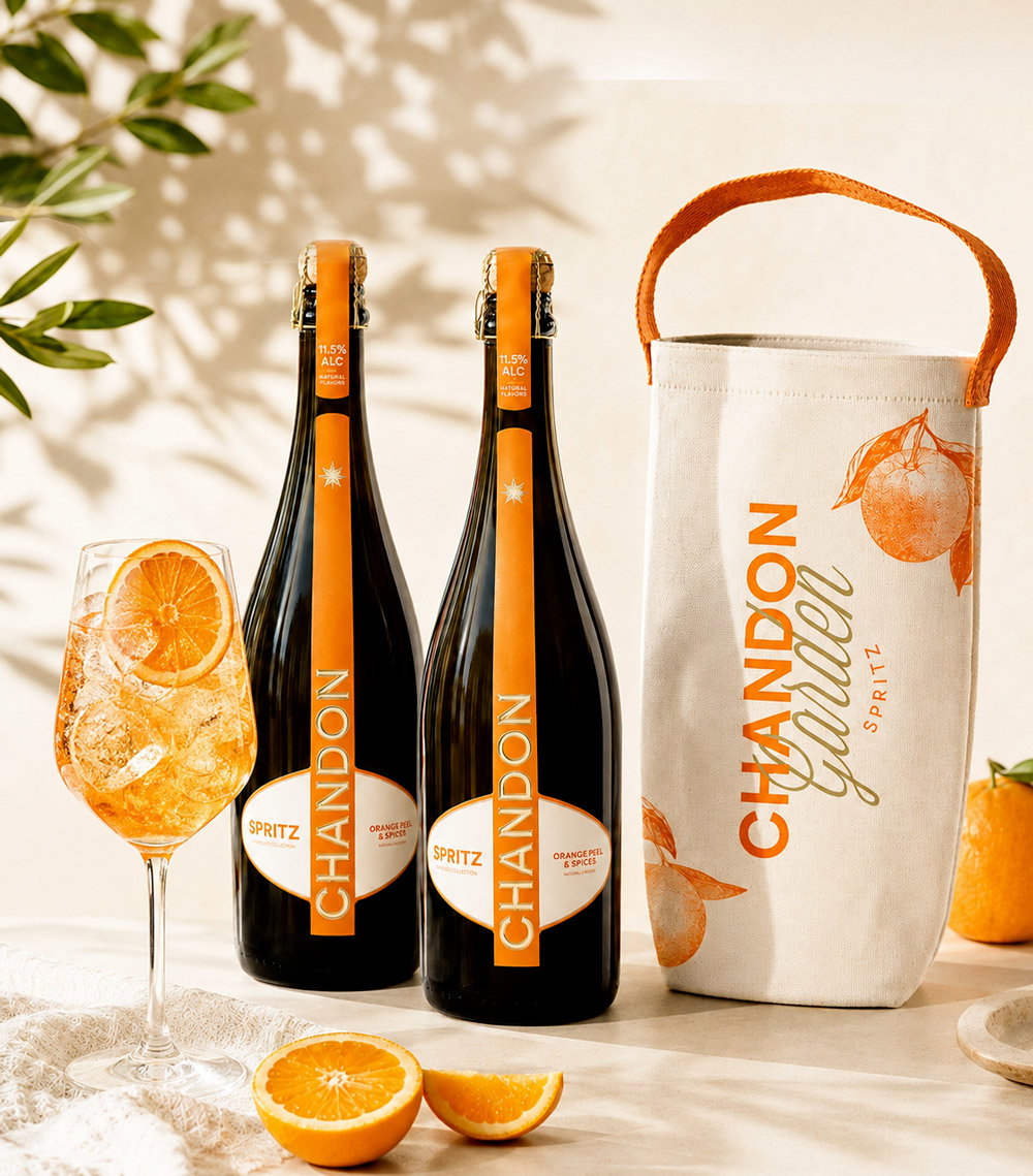 Two Chandon Spritz bottles, a filled spritz glass with orange slice, sliced oranges and a branded tote bag
