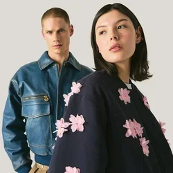 Due modelle indossano giacche alla moda, una in giacca di pelle blu, l'altra in giacca blu scuro con applicazioni floreali rosa in rilievo.