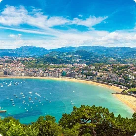Aerial view of a sandy beach and bay lined with boats in Barcelona.