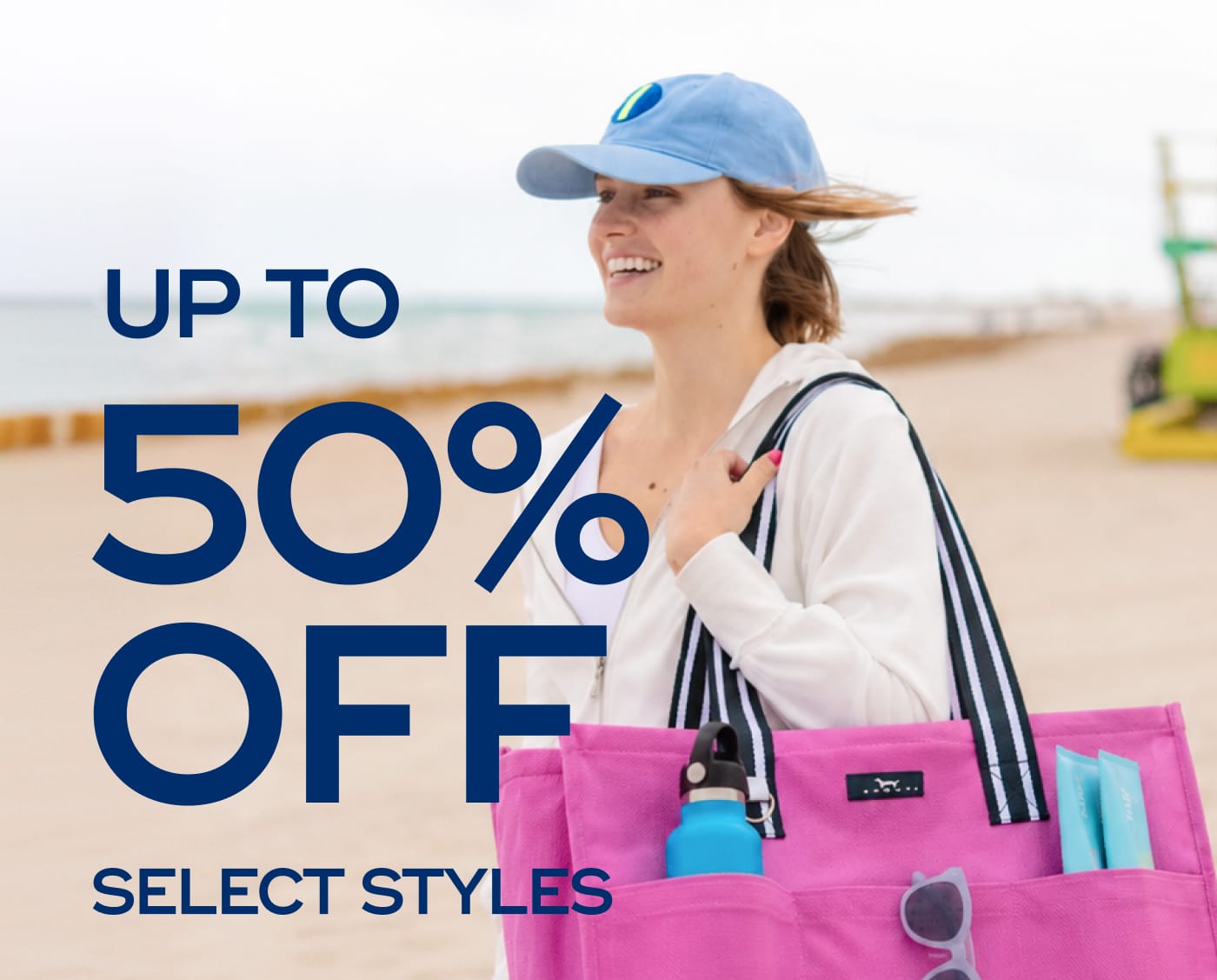 UP TO 50% OFF SELECT STYLES. Woman on a beach carrying a pink SCOUT bag.