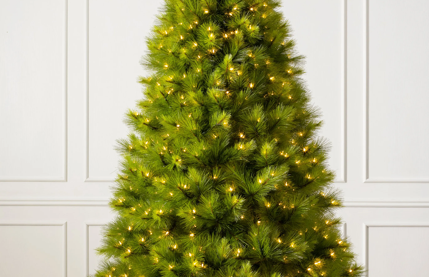 Close-up of a pre-lit artificial Christmas tree with bright green branches and warm white lights.