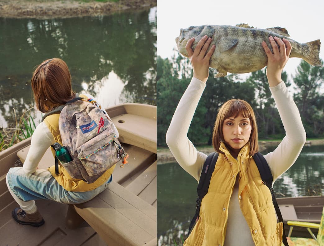 A woman wearing a yellow gilet and a JanSport bog core camo bag holding a large fish over her head