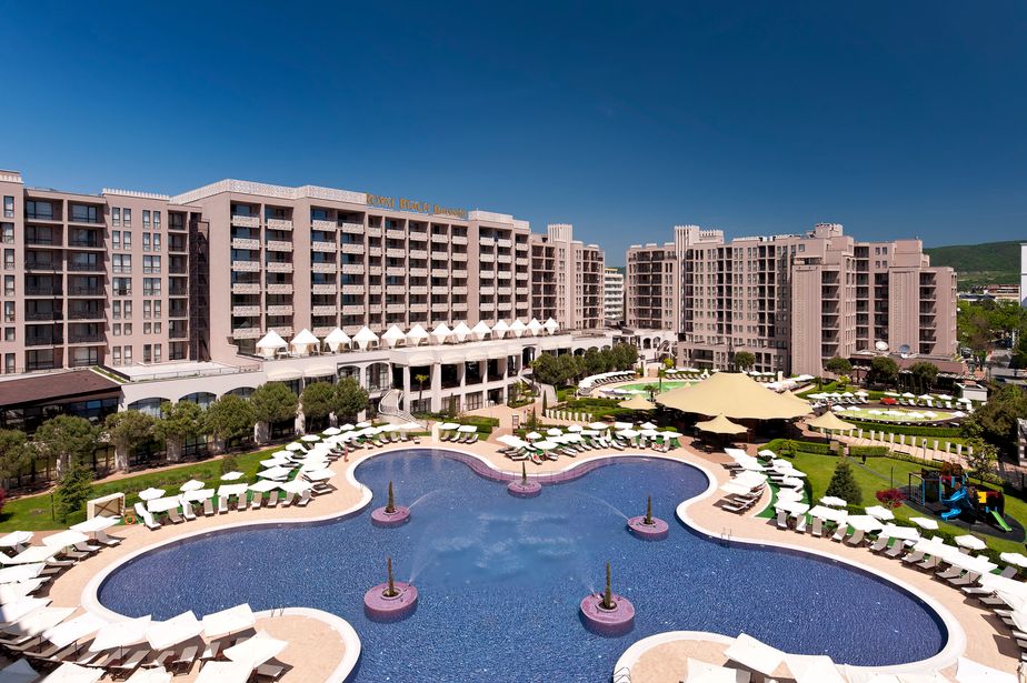 Luxury resort hotel with expansive freeform outdoor pool, rows of sun loungers and parasols amid manicured gardens