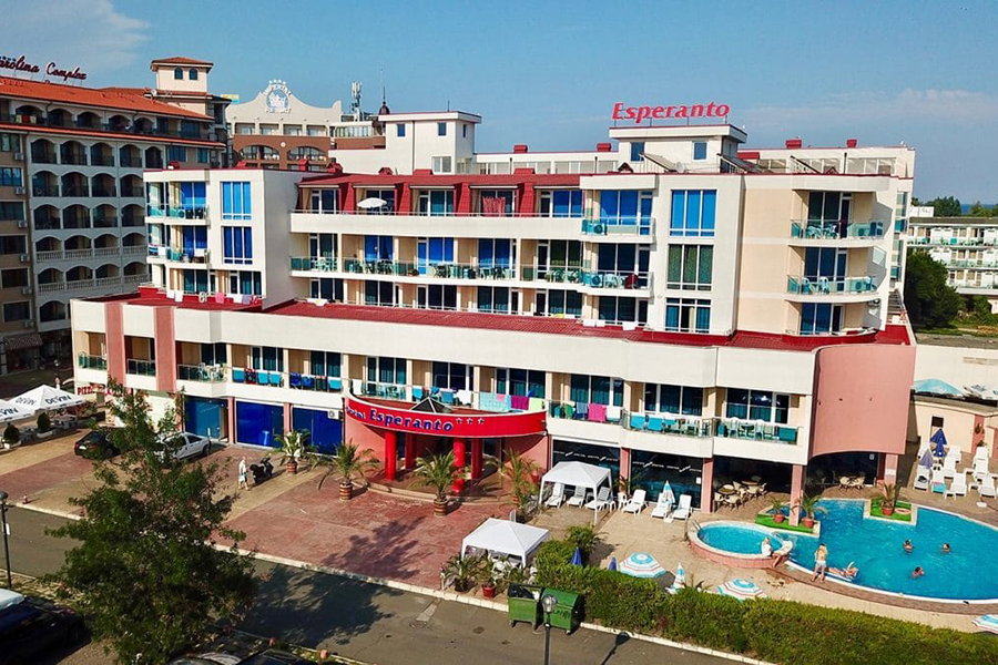 Esperanto hotel facade with balconies, outdoor swimming pool, sunbeds and guests at a sunny seaside resort