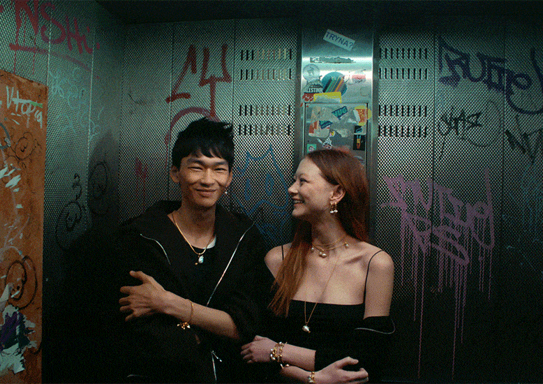 Two models stand and smile in an elevator