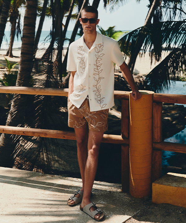 Man wearing an Ecru Pure Cotton Embroidered Short Sleeve Shirt and Butterscotch Quick Dry Embroidered Swim Shorts