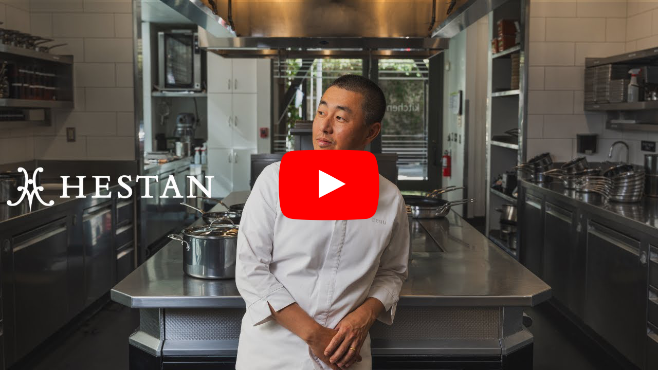 IMG: Chef Corey Lee standing in the kitchen. YouTube play button on top.